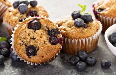 Blueberry-Banana Protein Muffins on table with scattered blueberries
