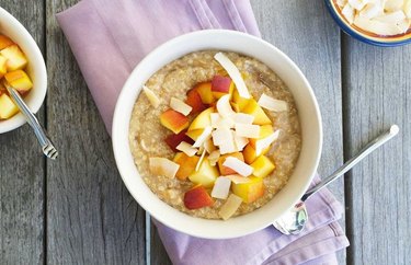 Coconut Quinoa Oatmeal Bowl with peach slices and a spoon
