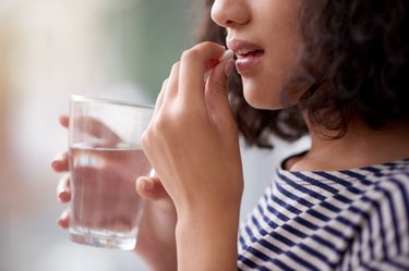 Close-up shot of woman holding a glass of water and taking vitamin d3 for weight loss testimonials about IU fat
