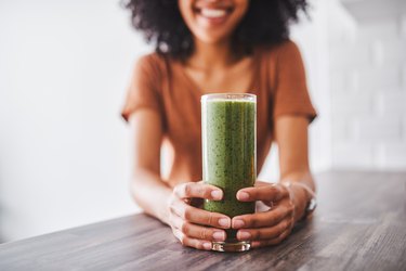 Woman holding green drink.