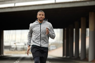 Portrait of young athlete jogging on road in city