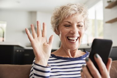 Senior woman video calling on smartphone at home, close up