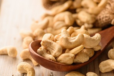 close up of zinc-rich cashew nuts in wood spoon on wood table
