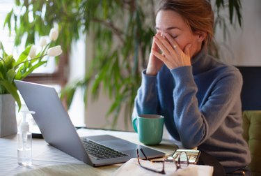 a woman sitting at her desk and rubbing her eyes because of sudden extreme fatigue