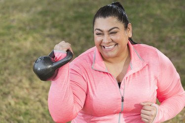 hispanic plus-sized athlete wearing pink, holding a kettlebell in the rack position