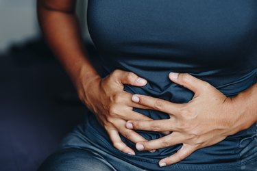 close up of a person holding their bloated upper abdomen in pain