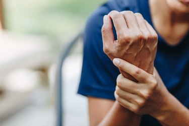 close view of a person holding their wrist because of arthritis pain, to represent statistics of arthritis