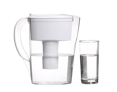 water filter jug with glass of clean water isolated